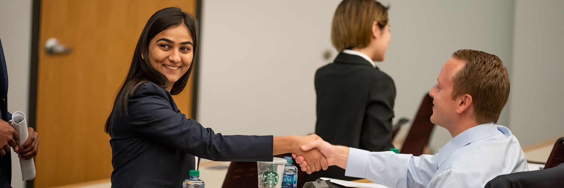 An MS in Information Systems student shakes hands with a judge during a case competition. 
