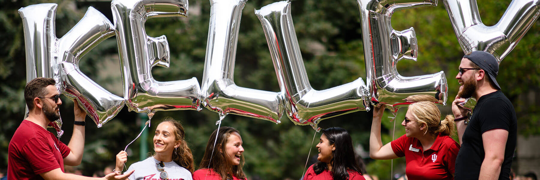 Group of Kelley School of Business students and staff holding silver balloons that spell out Kelley.