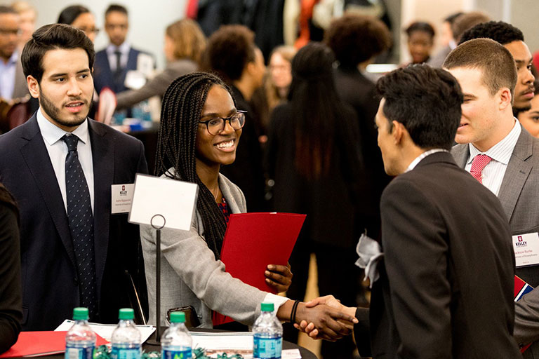 young woman shaking hands networking with fellow alumni