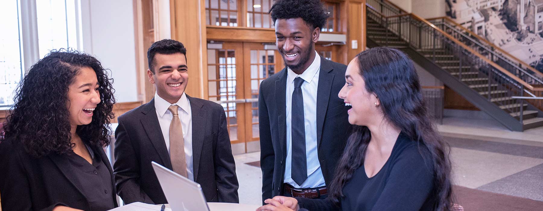 A group of four undergraduate Kelley School of Business students talking and smiling at each other in Hodge Hall. 