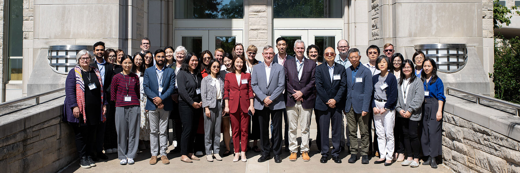 A group of people who participated in the Innovations to Tackle Global Sustainability Challenges Conference stand together in front of the Godfrey Building on the IU Bloomington campus.