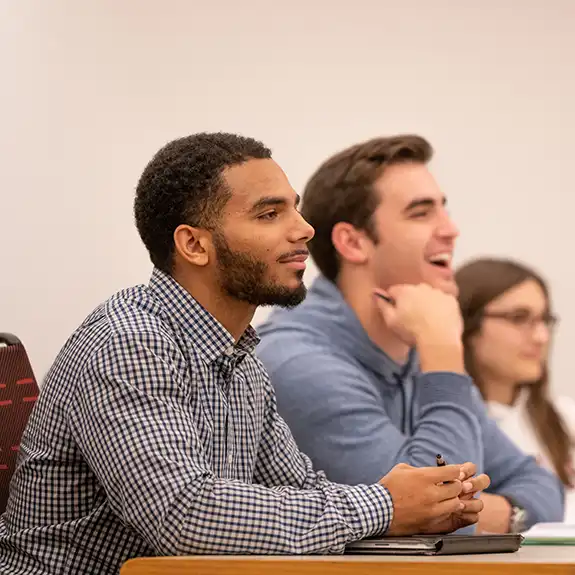 Undergraduate student raising his hand in class.