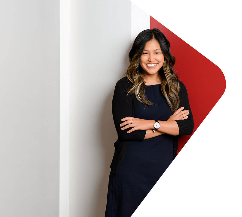 A Kelley MBA student wearing a black dress stands in front of a red and white backdrop.