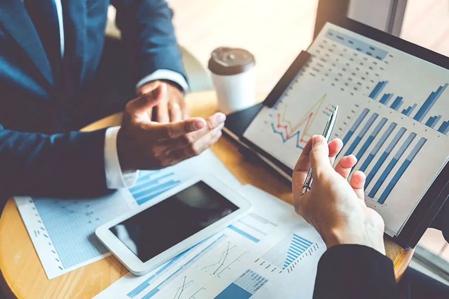 Two professionals are reviewing financial data during a meeting, demonstrating the types of skills developed with an online master's in finance.