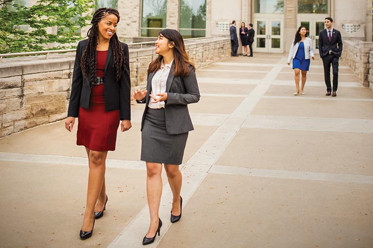 Outside of the Godfrey Graduate and Executive Education Center, Indiana University business graduate students smile while talking