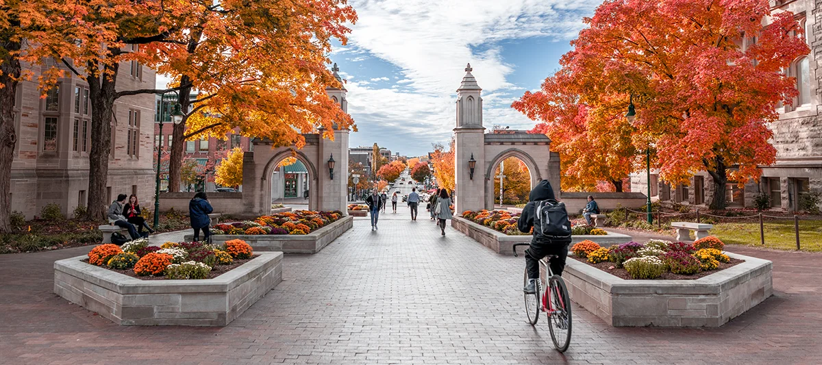 Students walking and biking near the Sample Gates on IU Bloomington campus